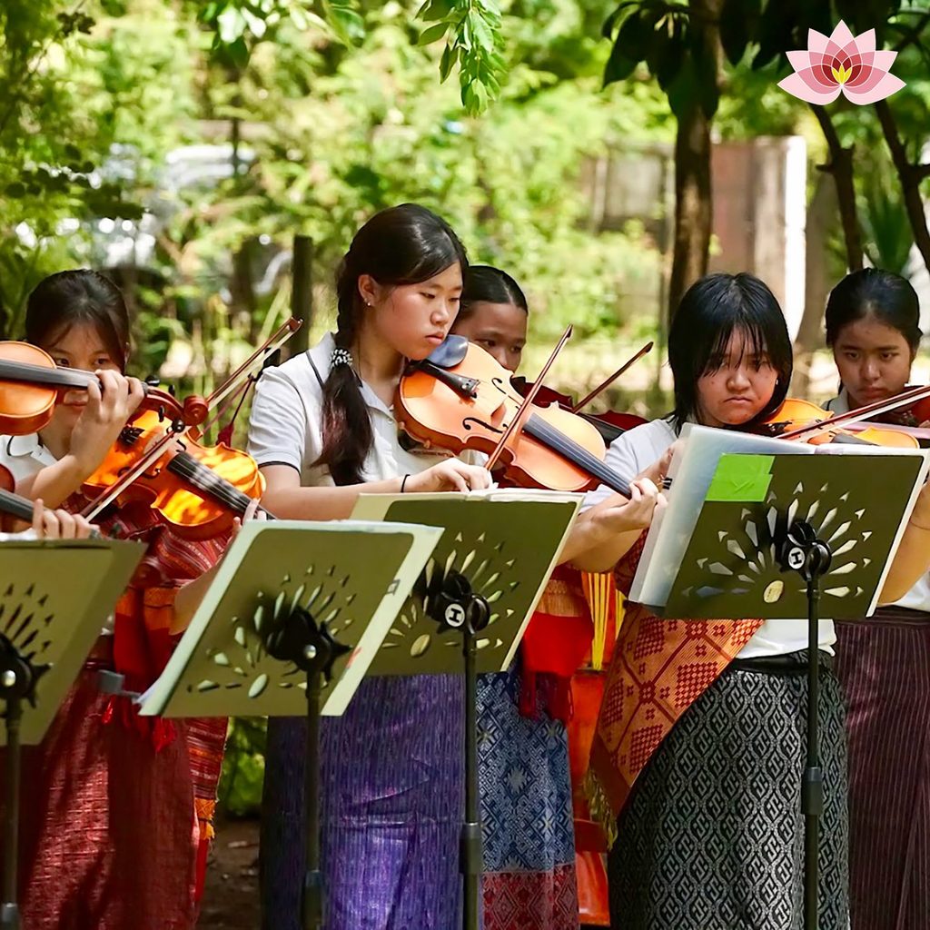 นักเรียนบรรเลงดนตรีเครื่องสายท่ามกลางบรรยากาศร่มรื่นของโรงเรียน